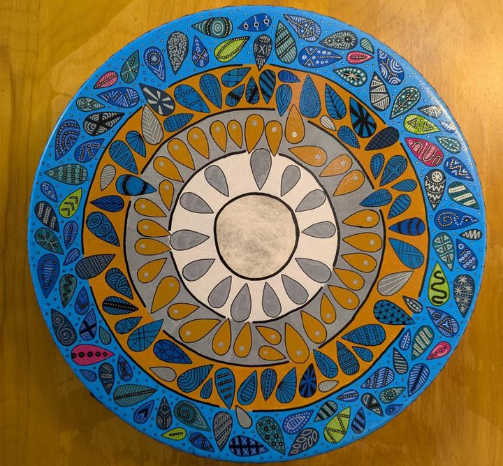 An elaborately painted from showing concentric circles of color populated by a wide variety of teardrop shapes