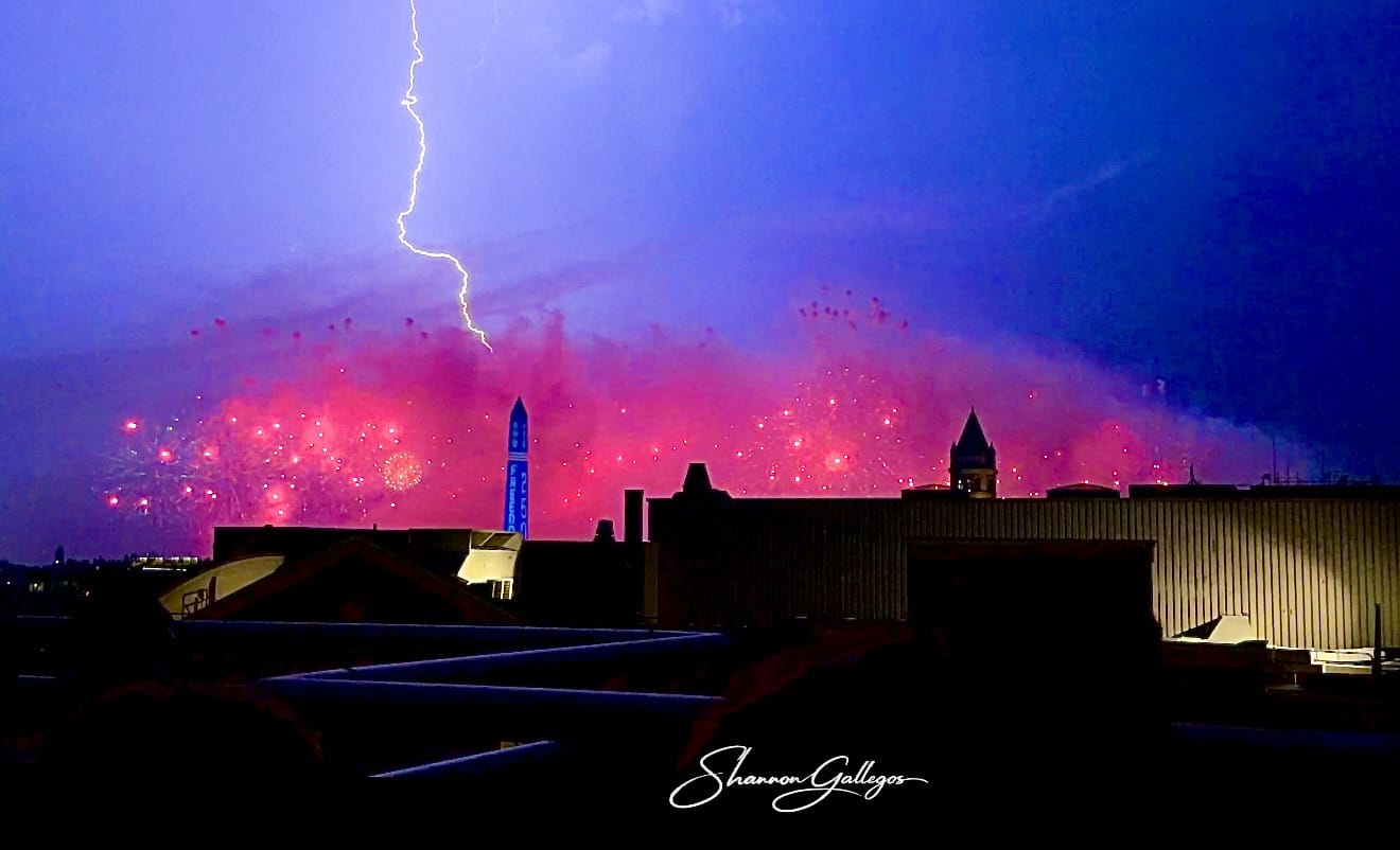 Photo of lightning striking near Washington Monument during Independence Day fireworks.