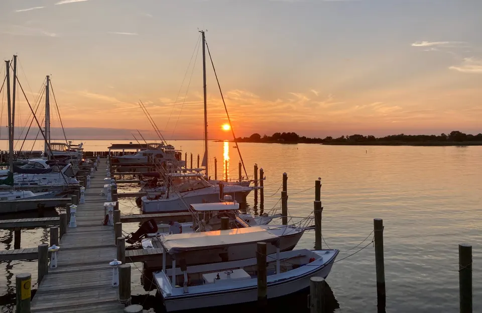 Boats docked with the setting sun in the distance.