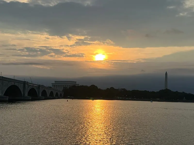 Photo of sun rising through mixed skies above the Potomac on Monday.
