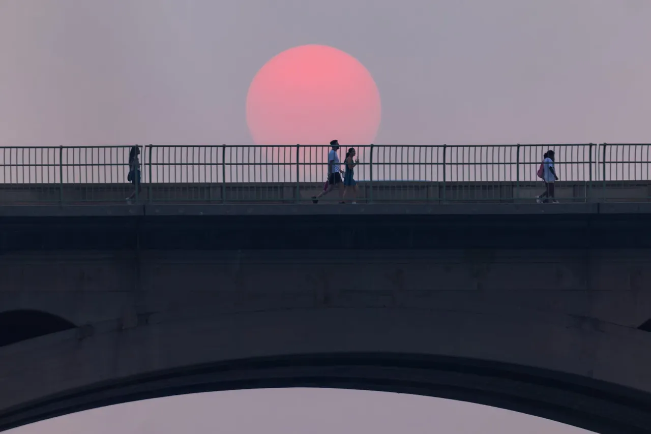 The setting sun is turned pink by a smoky haze.
