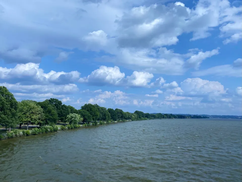 Mix of puffy clouds and blue skies over the tree-lined Potomac River.