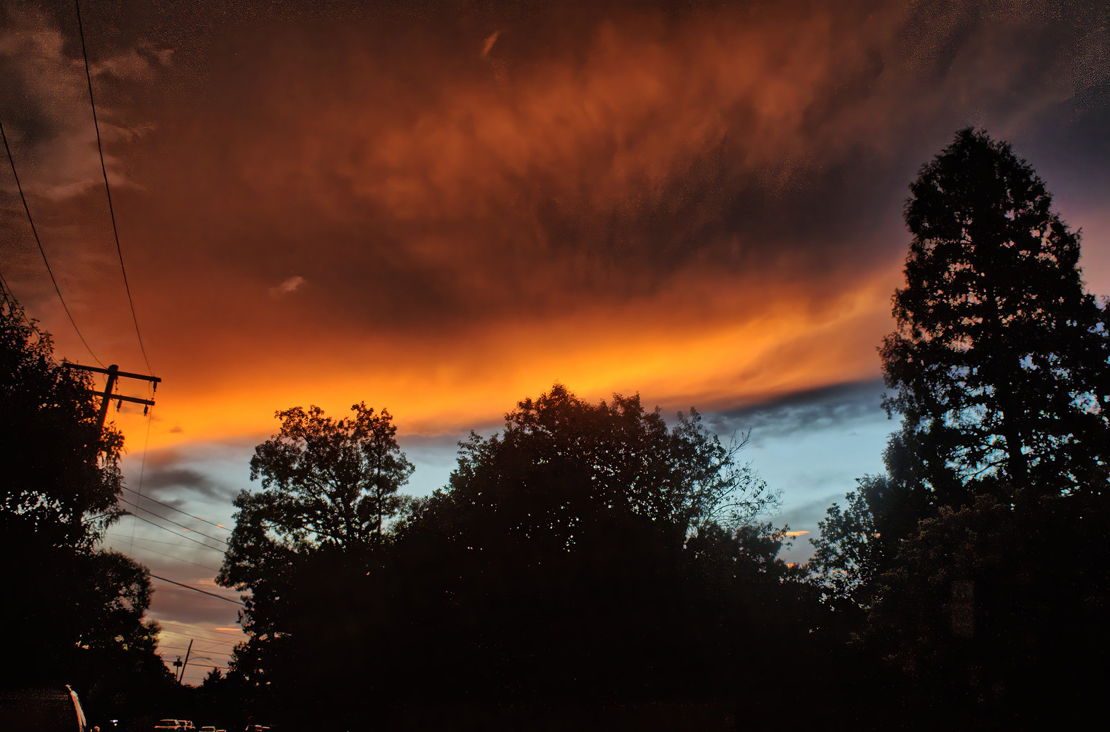 A glowing orange and yellow sunset with blue sky and trees also showing. 