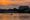 Orange sky and water on the Potomac with rowing crews passing the Lincoln Memorial