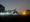 A foggy night scene with trees and obscured lights at night. 