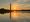 Just a few clouds over the water of the Tidal Basin as the Monument reflects along with a slightly orange sun with a bit of haze