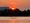 An orange sunrise with rowers on the Potomac River. They are in front of the Lincoln Memorial which is on the left.