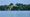 Mount Vernon from the Potomac River. The Potomac is in the foreground and the buildings are in the background with trees around them. 