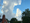 Brick house in the lower left corner has some blue sky overhead and cumulus clouds bubble up over the house