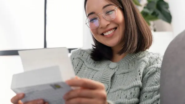 A woman reading a note and smiling back. 