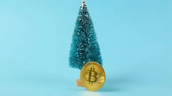 A Christmas stocking stuffed with physical Bitcoin tokens and a smartphone showing a crypto wallet.