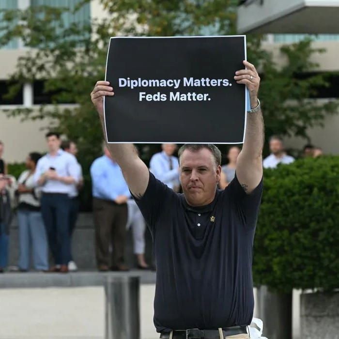 Photo of Michael Duffin holding up a poster that states, "Diplomacy Matters. Feds Matter."