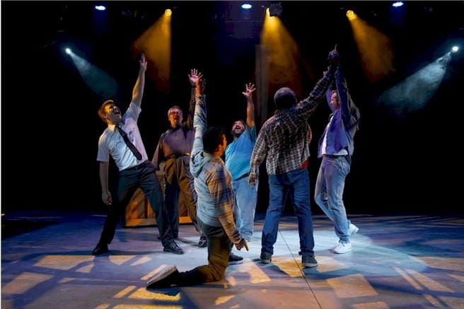 a group of men in a circle, arms raised in apparent triumph