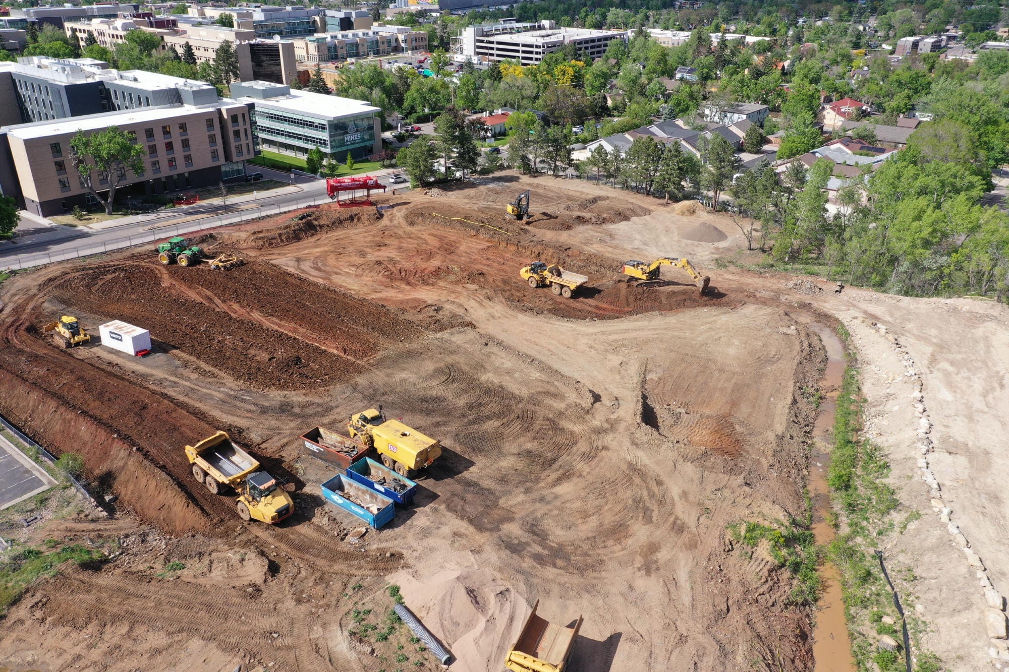 bulldozers grading the site, exposing reddish soil