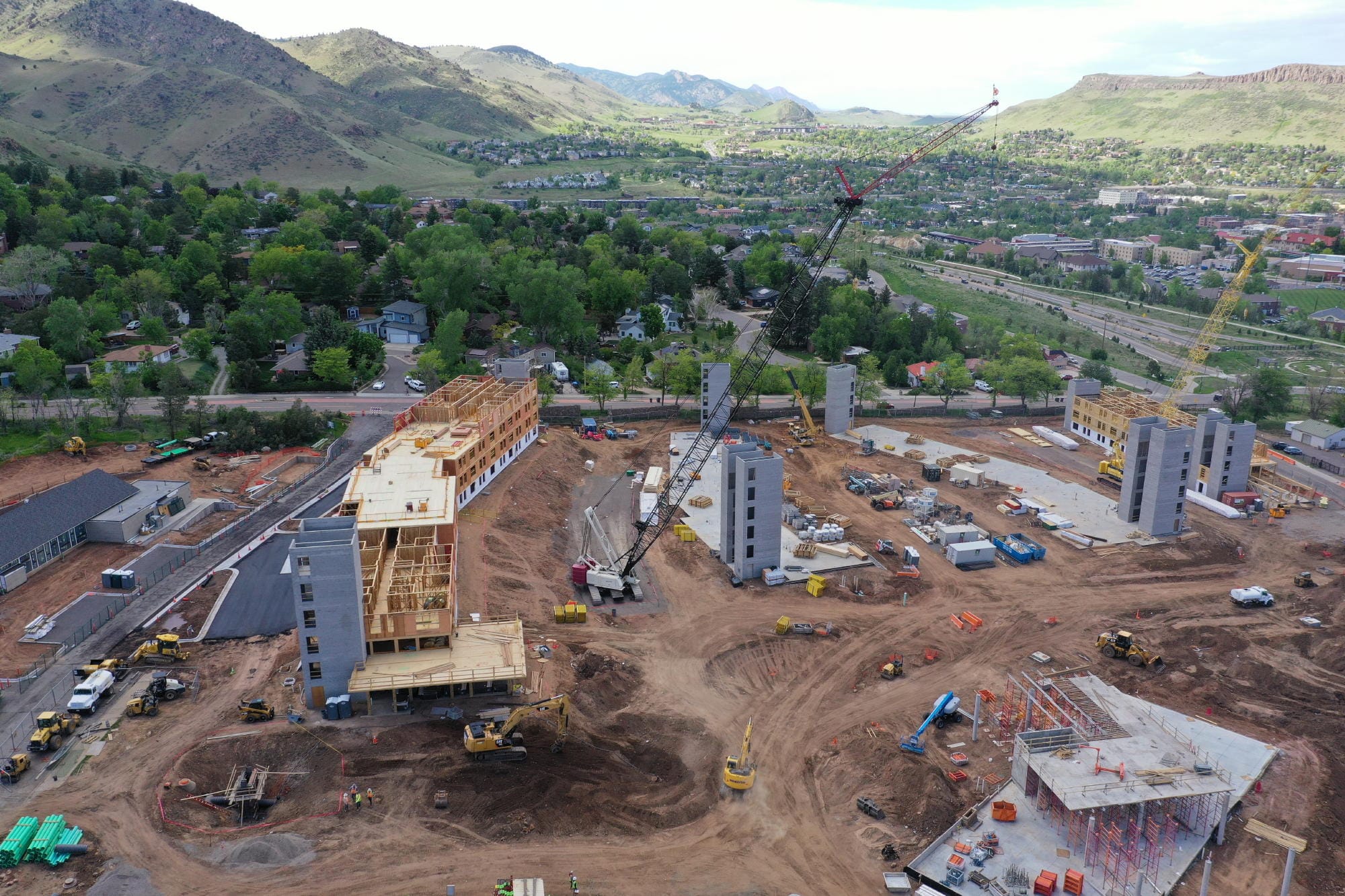 very tall cranes bringing construction materials to buildings in progress - some being framed with lumber