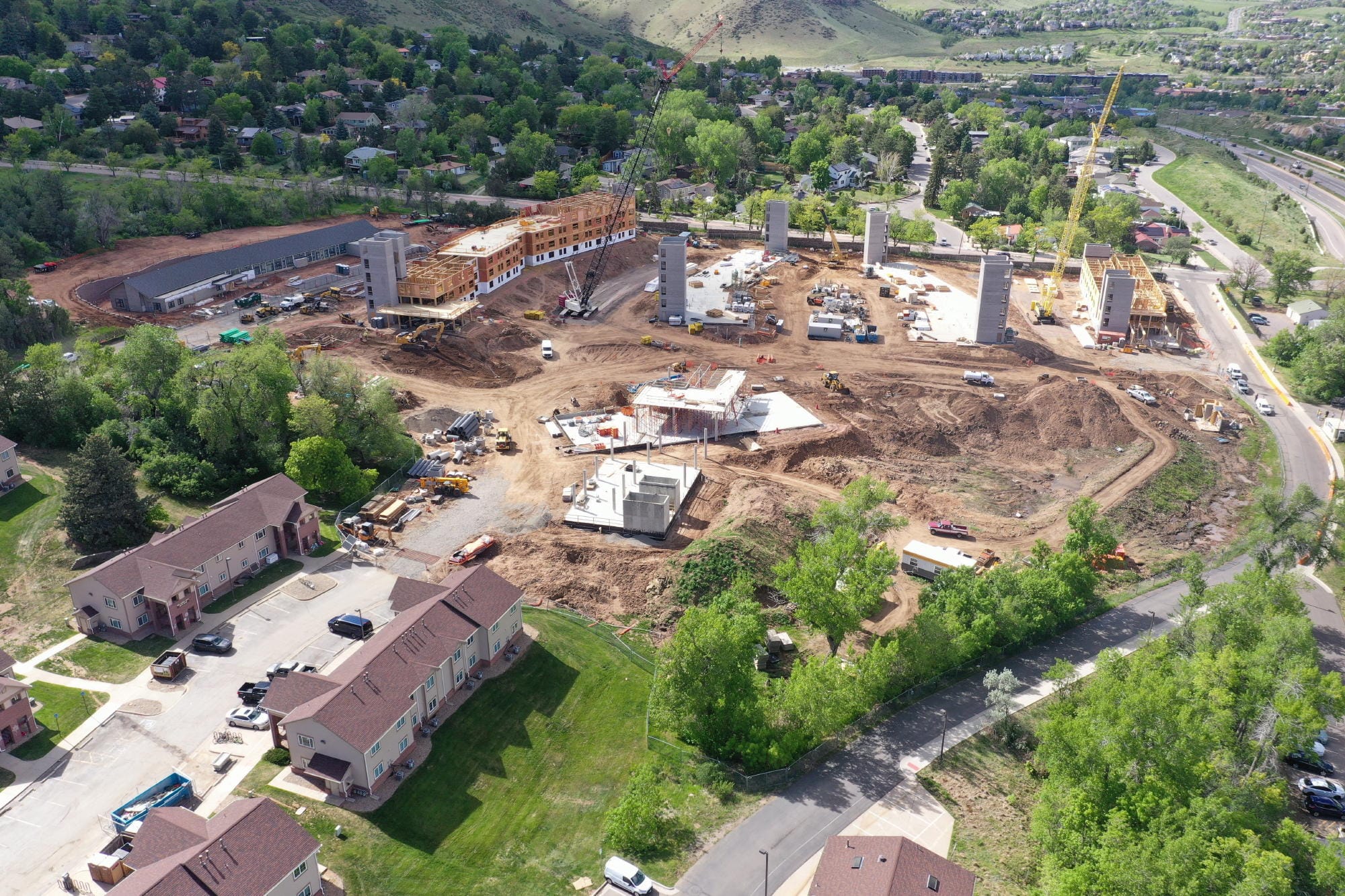 very tall cranes bringing construction materials to buildings in progress - some being framed with lumber