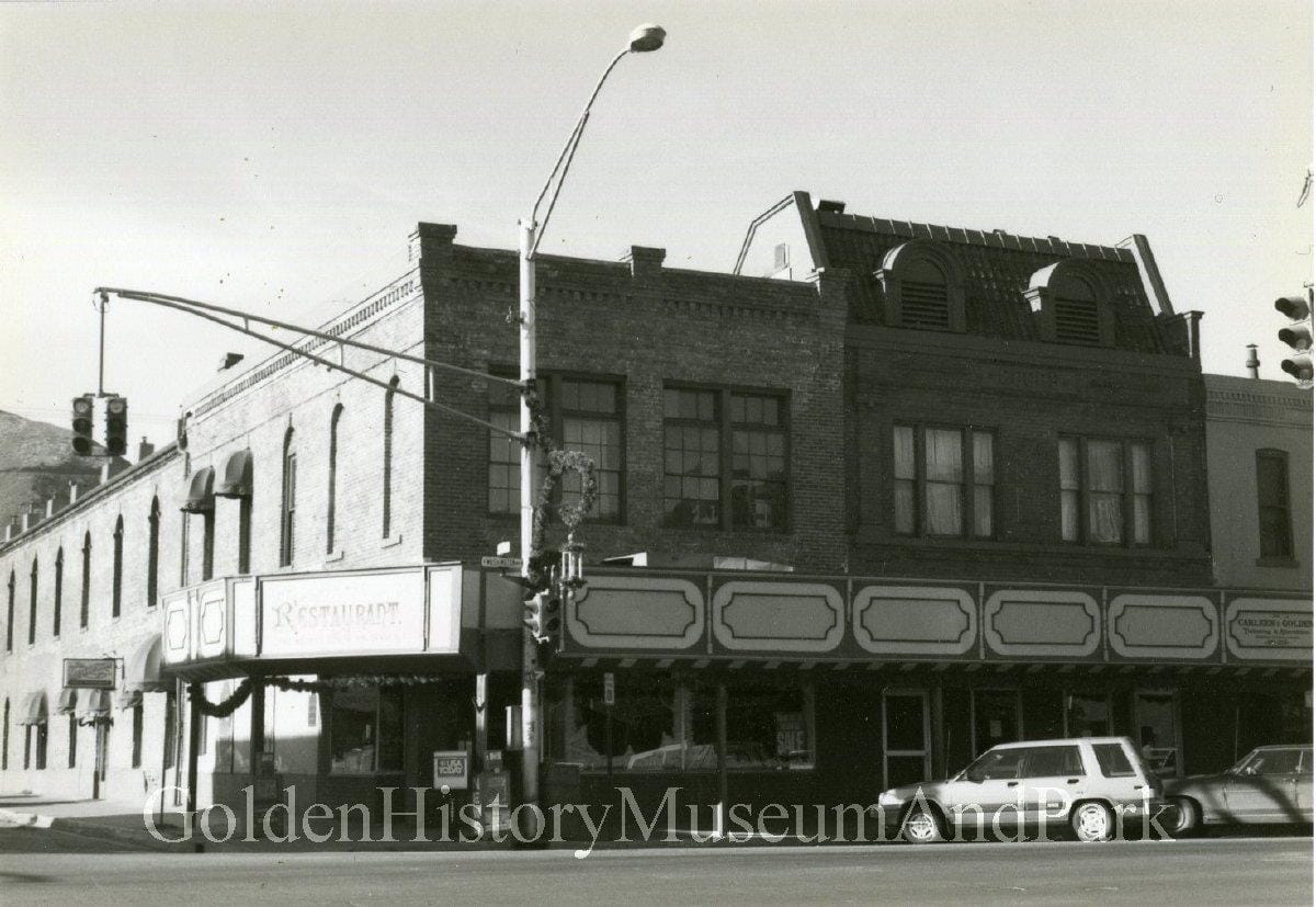 2 story brick building with a row of sign boards between the first & second floors