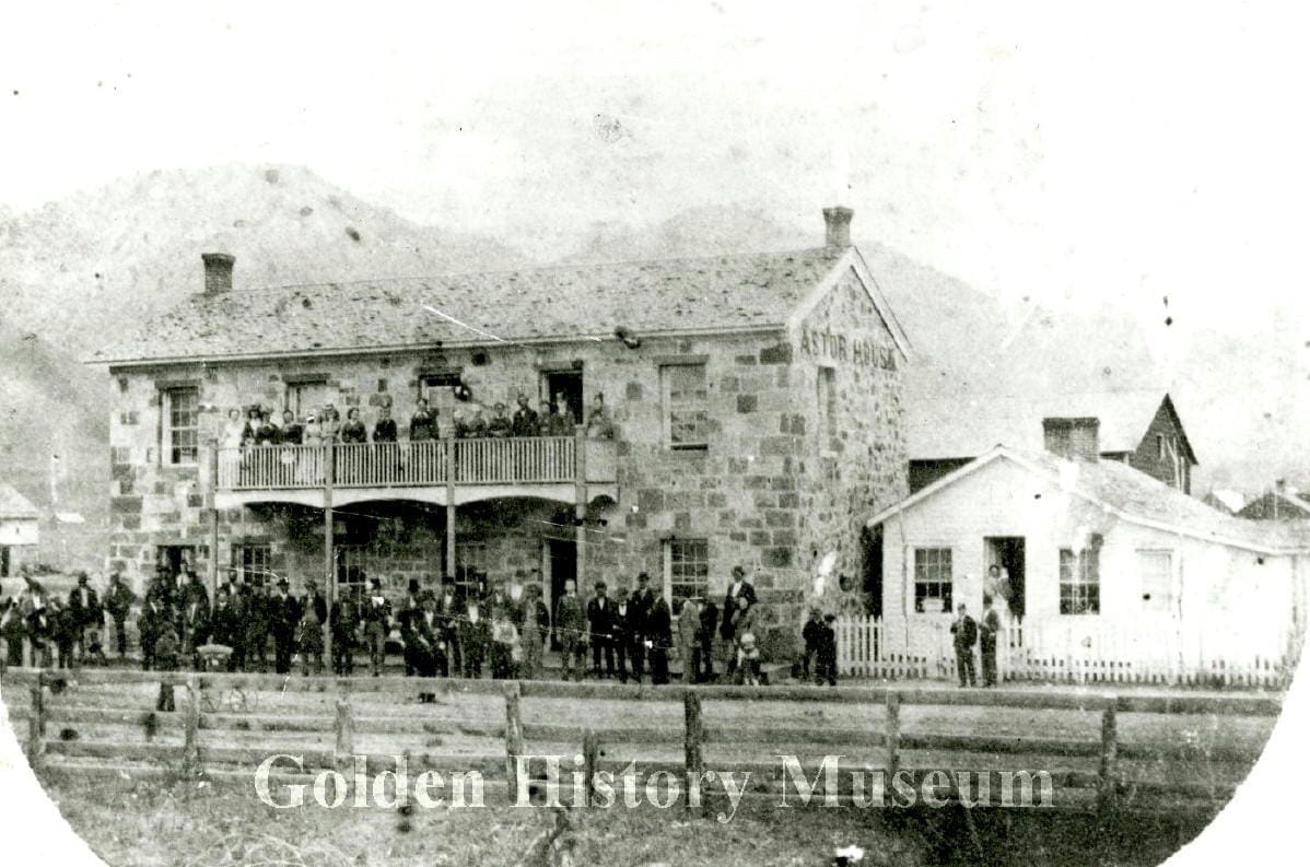 crowd of people stand in front of the Astor and on the 2nd floor balcony