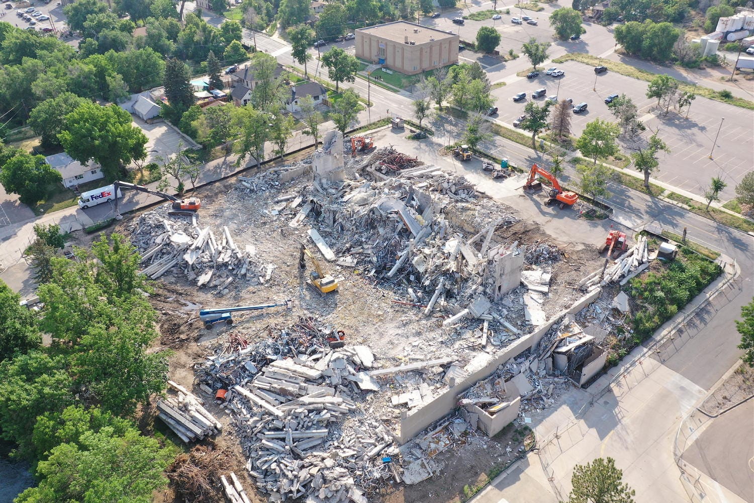several pieces of demolition equipment amidst piles of rubble where the building used to be