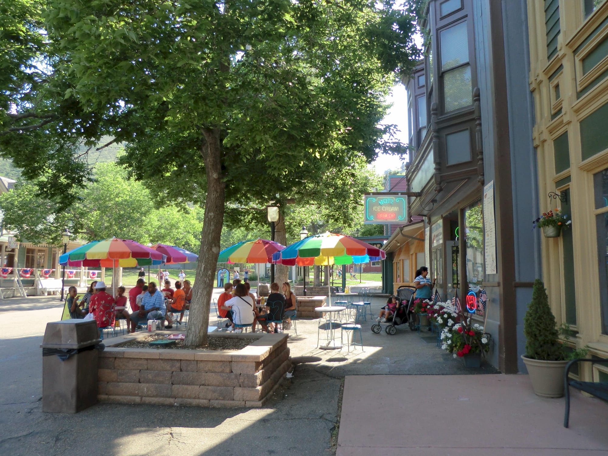 people sitting at outdoor tables under colorful umbrellas next to Victorian-style buildings