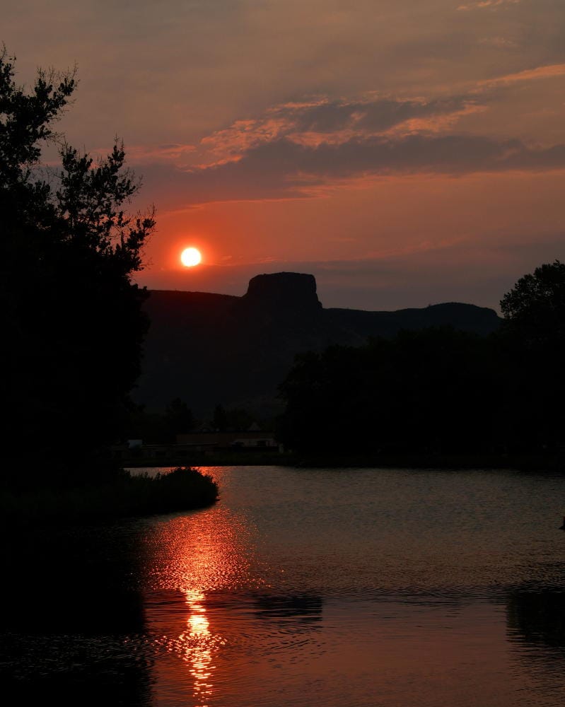 Castle Rock silhouetted against a dark red sky with a red-yellow sun clearing the mountain