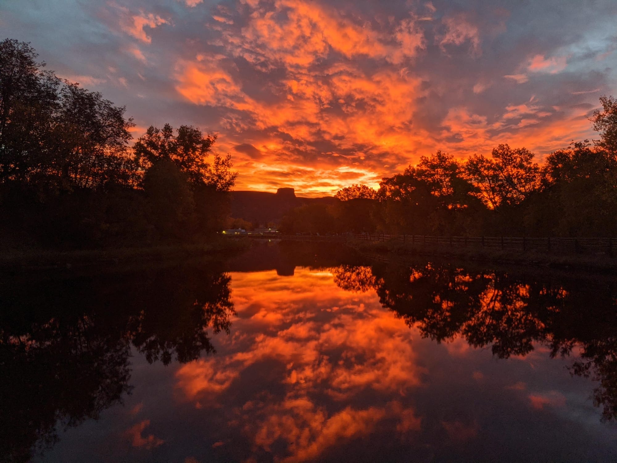 spectacular view of the sunrise from the west side of the city pond - fire-tinted clouds turning sky and water orange