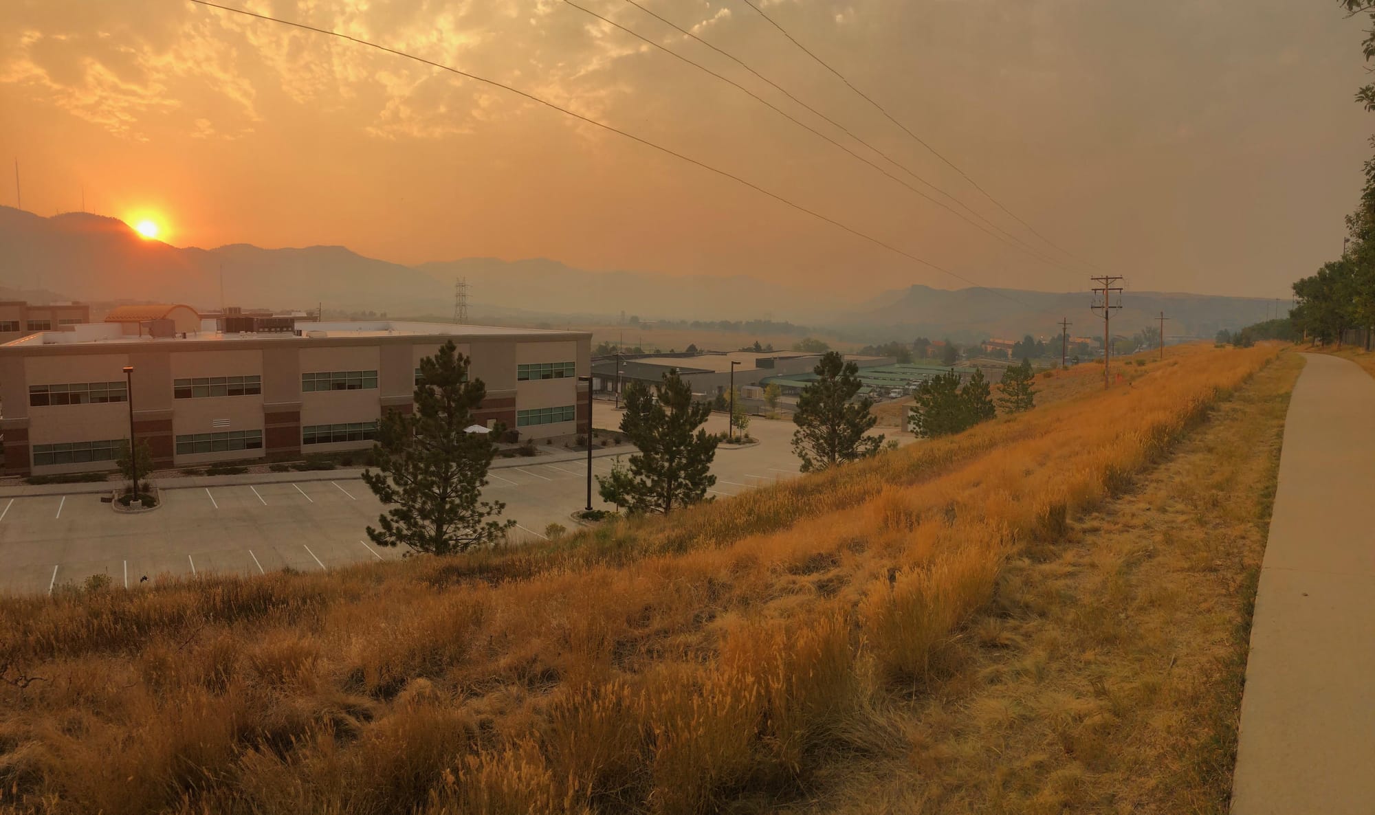 fiery sun setting behind the mountains with smoky air tinting the world orange