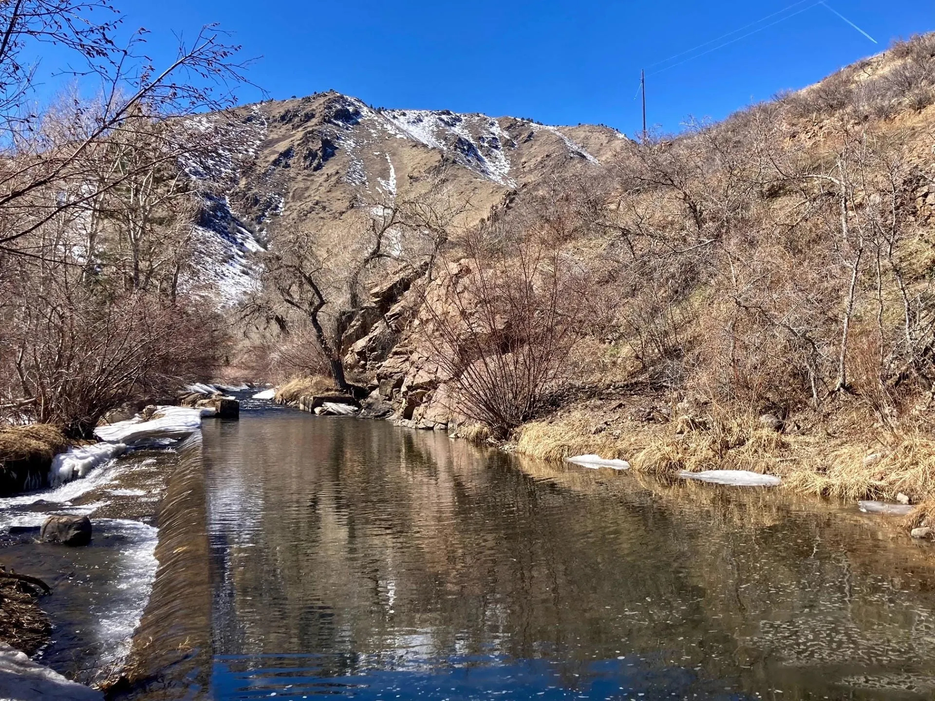 Chuch ditch with a small spillway at the edge.  Mountain with some snow in background.