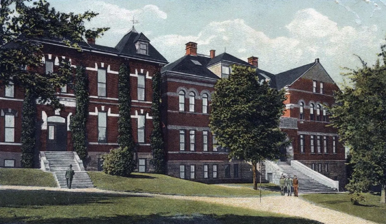 Large, long, 2-1/2 story brick building, several distinct section, with long white staircases leading to the first floor