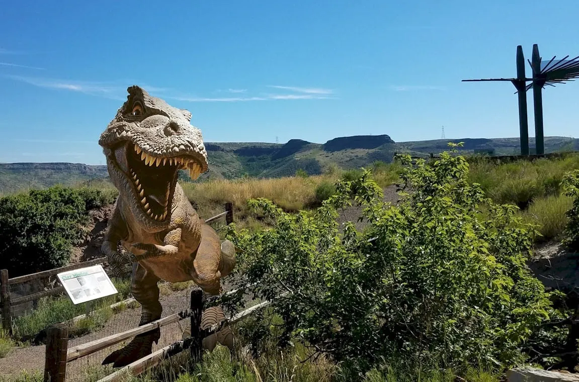 photo of Triceratops Trail, South Table Mountain in background, with clip art t-rex standing on trail