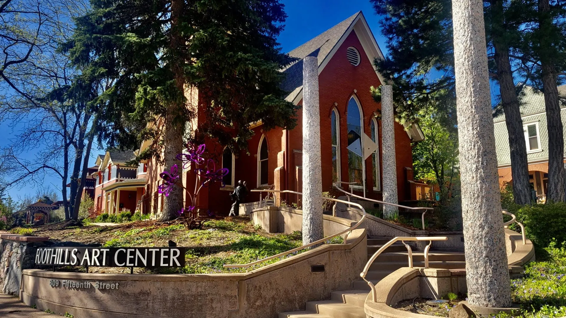 curved concrete stairs leading up to old red brick church - sign in front saying FOOTHILLS ART CENTER