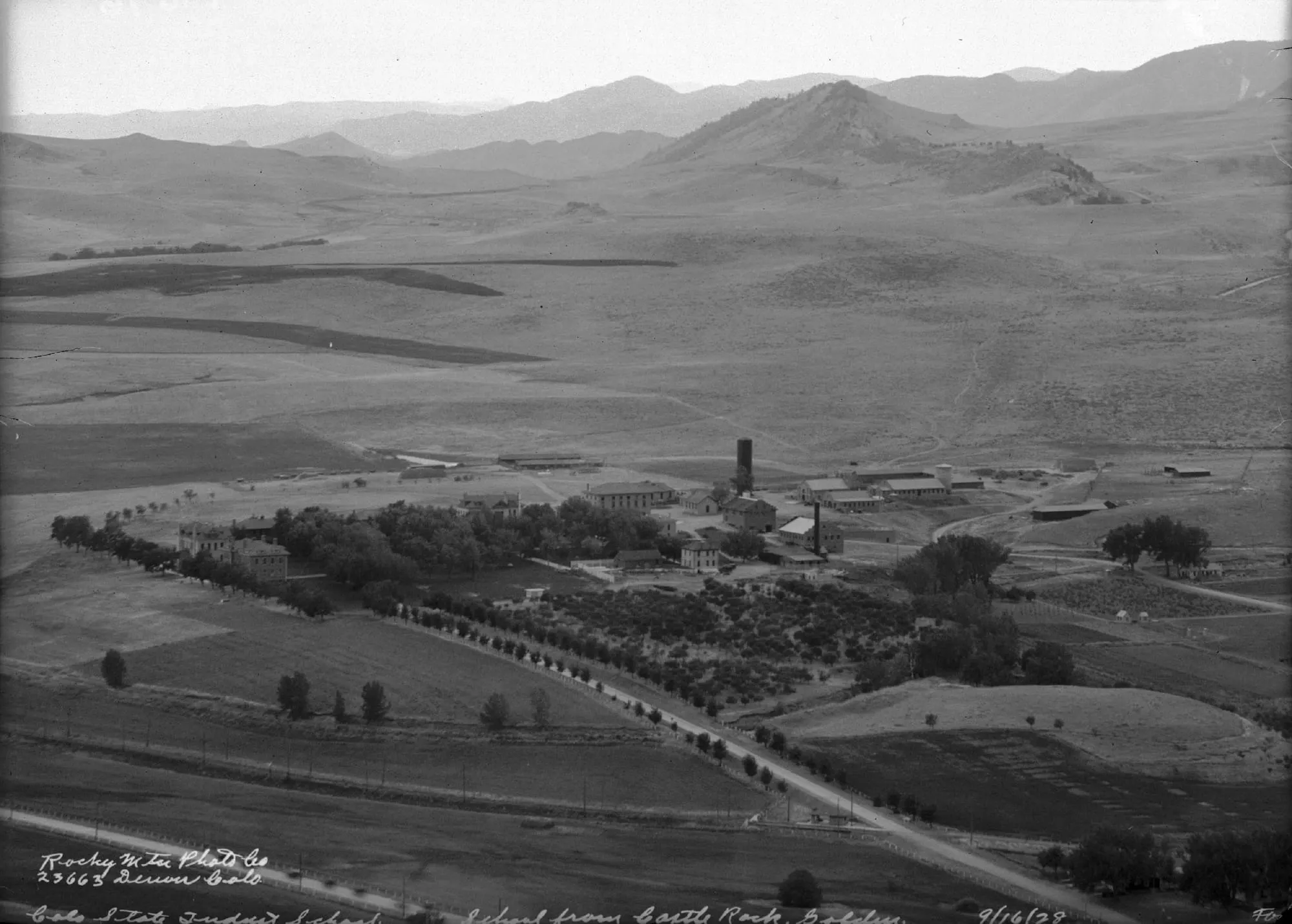 Industrial School property with trees and plowed fields, surrounded by plains and mountains. 