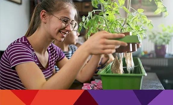Teenaged girl lifting a plant to look at the roots