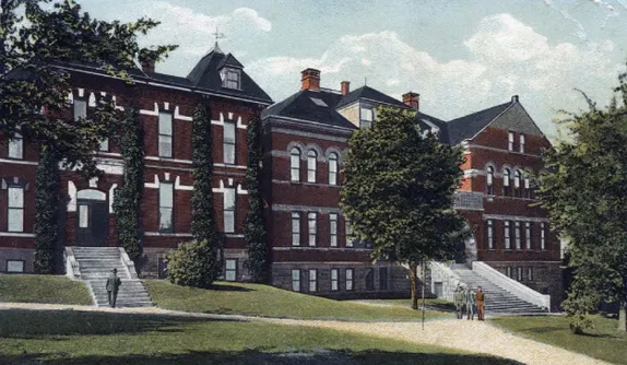 Large, long, 2-1/2 story brick building, several distinct section, with long white staircases leading to the first floor