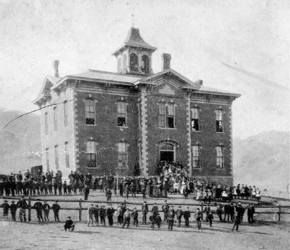 two story brick building with cupola and scores of students standing in front