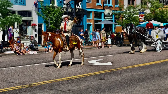 Buffalo Bill on a paint gelding (Sonny), followed by a Clydesdale (Wallace) pulling a white carriage