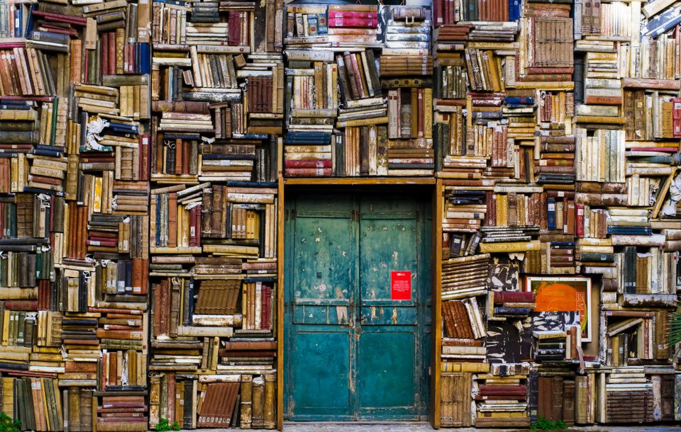 Super-stuffed bookshelves surrounding a blue-green door.