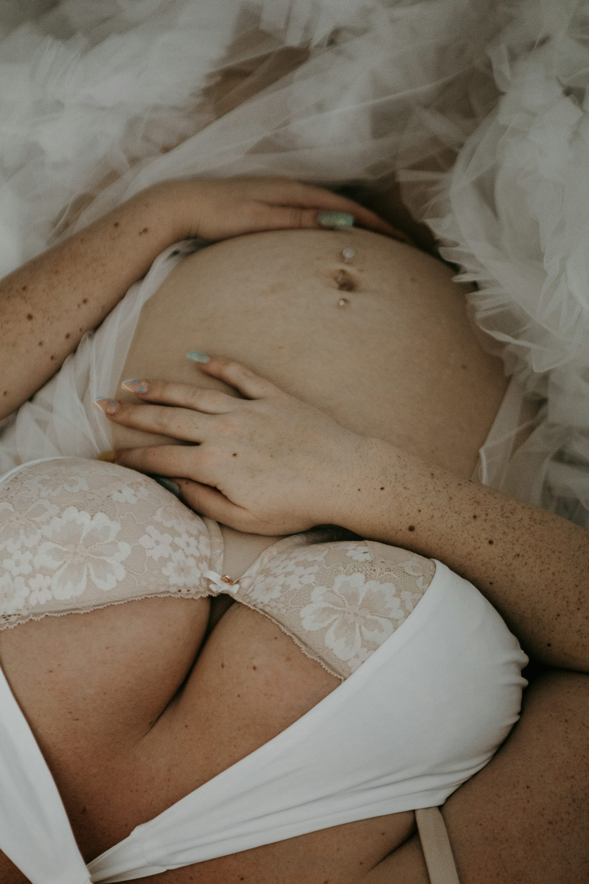Pregnant woman in a white bra with hand on her belly
