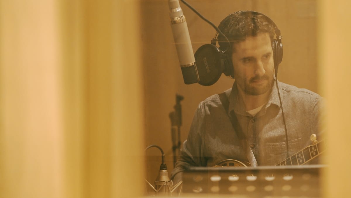 Max Wareham looking pensive in the recording studio, holding his banjo. Photo by Kaitlyn Raitz.