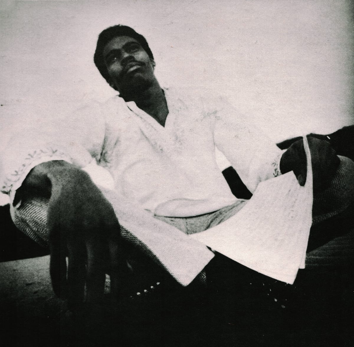 Bayeté (Todd Cochran) in white clothing, vintage black and white photograph from 1973 album back cover, shot from low angle.