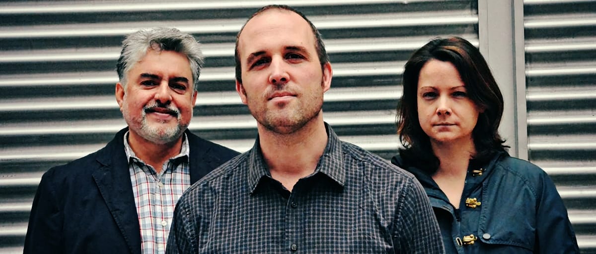 Tony Malaby, Nick Fraser, and Kris Davis stand close together before a corrugated metal shutter, looking directly at the camera.