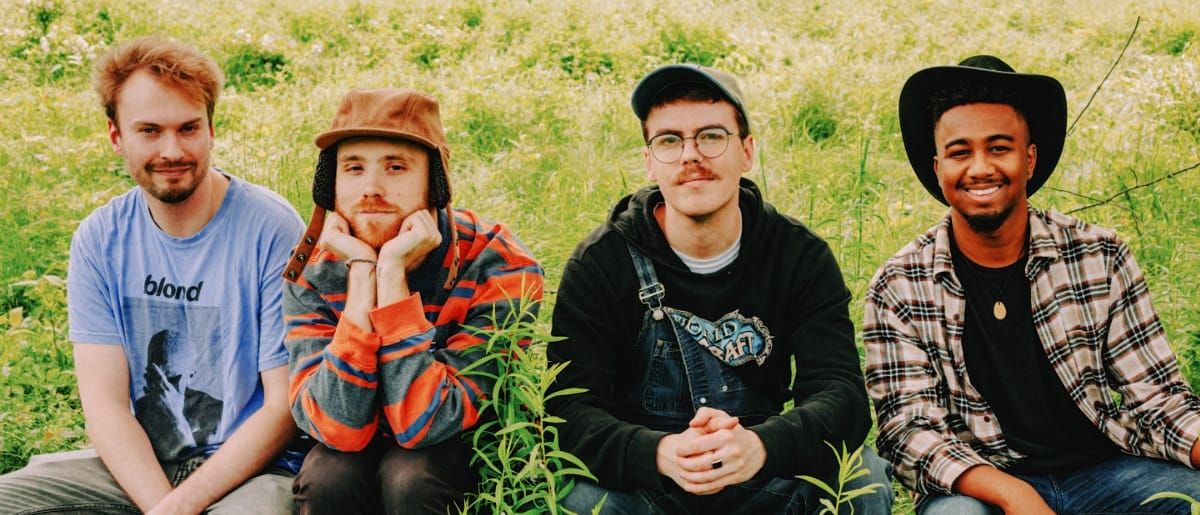 The four members of Tiberius sitting in the grass. Photo by Zoe Hopper.