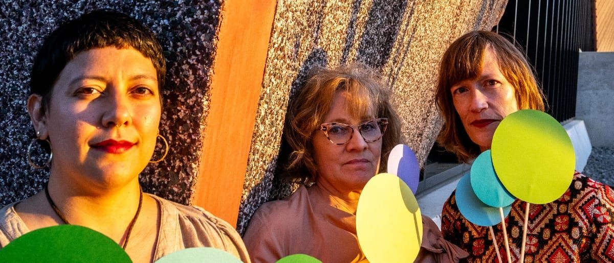 Beatriz Ramirez-Belt, Holly Tavel, and Sarah Morrison of Lost Noises Office against textured backdrop with colorful balloons. Photo by Jim Leatherman.