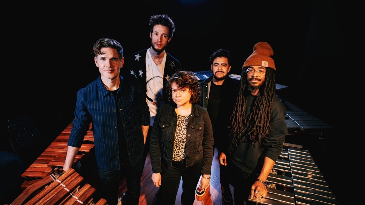 Ben Wendel and his BaRcoDe ensemble cluster between a marimba and vibraphone on a darkened stage, five musicians looking directly into the camera. Photo by Gilad Hekselman.