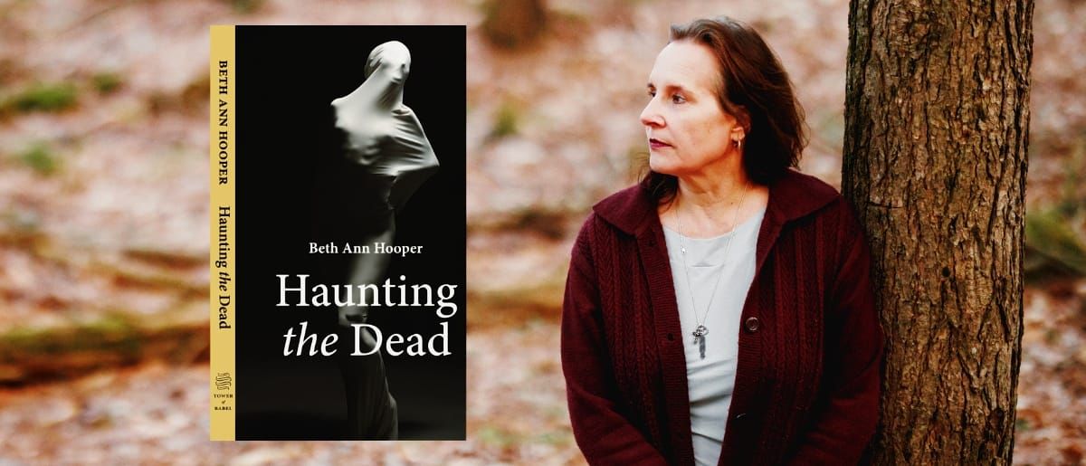 Beth Ann Hooper leans against a tree in a wooded autumn setting, alongside the cover of her book Haunting the Dead, which features a shrouded figure on a dark background.