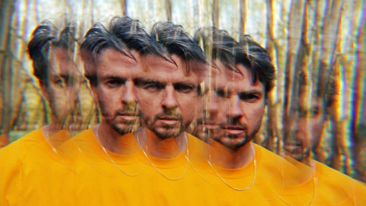 Tom Skinner in a yellow t-shirt, photographed with a prism or multi-exposure effect that multiplies his image across the frame against a wooded backdrop. Photo by Jason Evans.