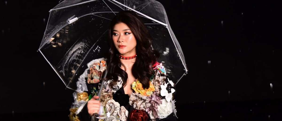 Erika Dohi holding a transparent umbrella, black background. Photo by Shervin Laine.