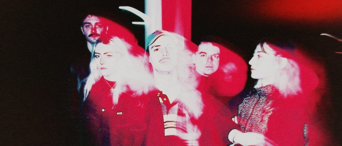 Five members of French band wavepool stand together under dramatic red and white lighting, creating a hazy, overexposed aesthetic. Photo by Charlotte Romer.