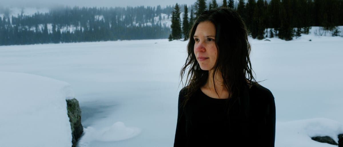 Isabel Pine in black clothing against snowy landscape with evergreen forest and misty atmosphere. Photo by Nelson Moneo.