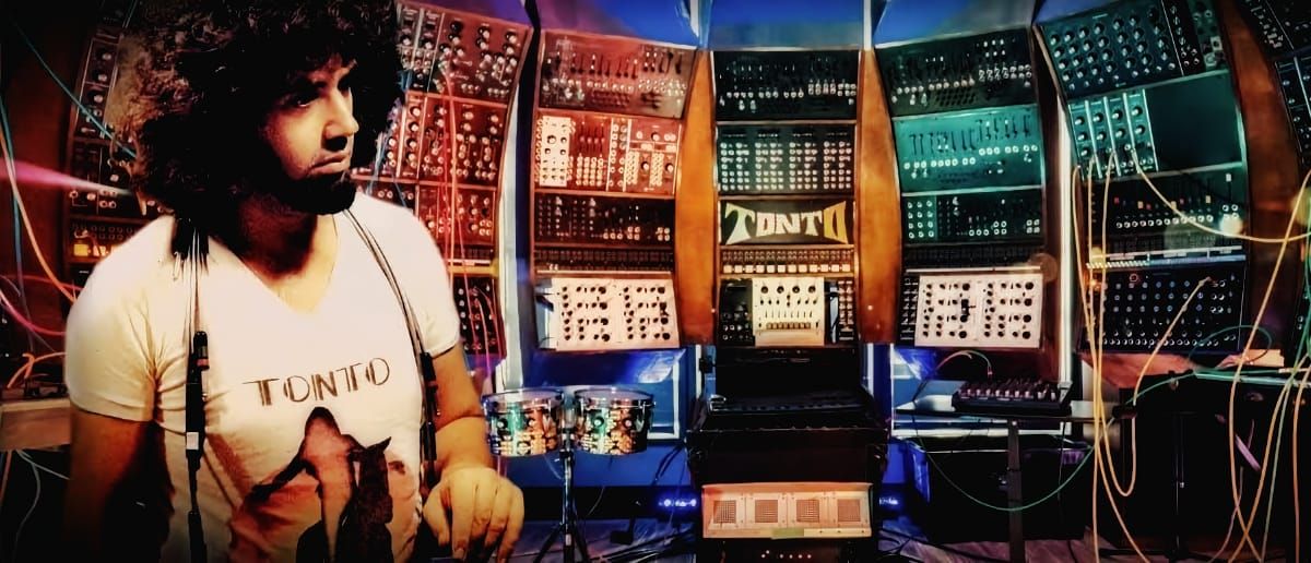 Robert Margouleff stands beside TONTO, a towering wall of modular synthesizer equipment, its patch cables spilling outward in every direction.